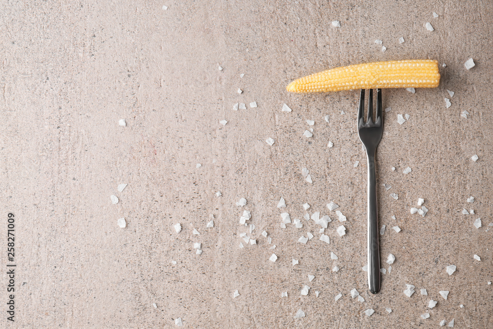 Fork with baby corn cob on grey table