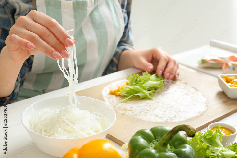 Woman preparing tasty spring rolls, closeup