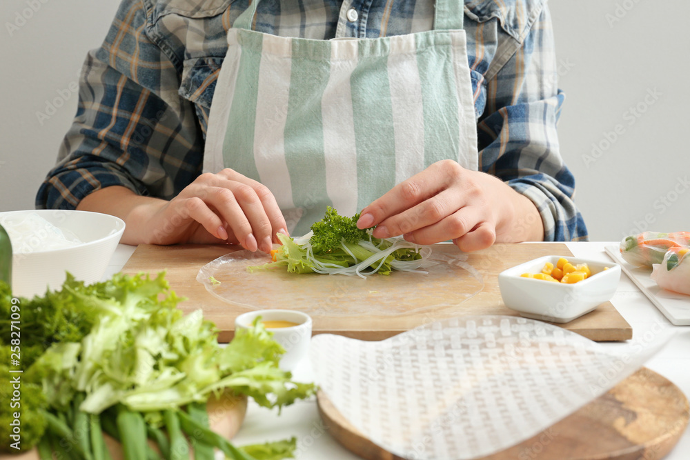 Woman preparing tasty spring rolls