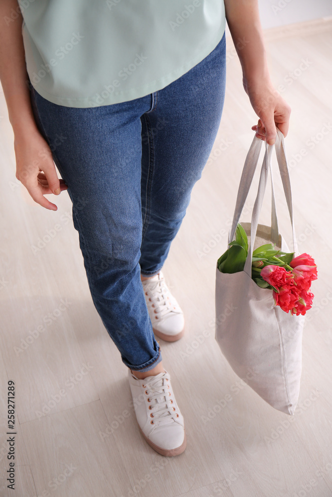 女人在室内拿着带花的环保袋