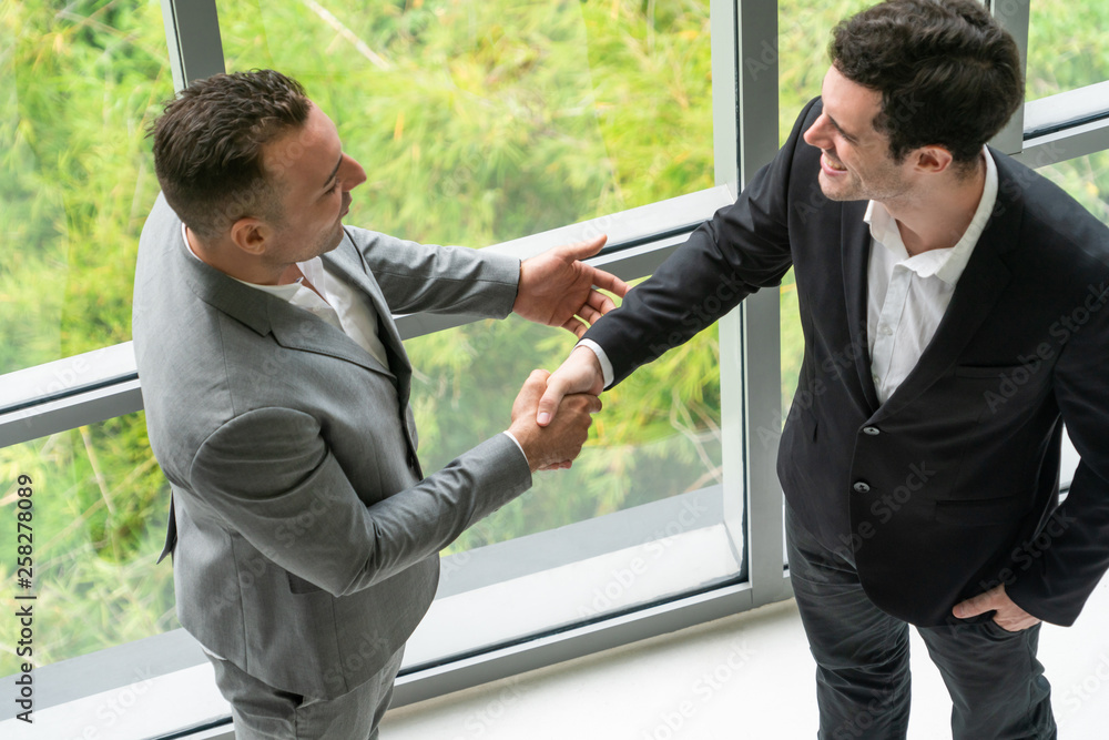 Businessman handshake with another businessman partner in modern workplace office. People corporate 