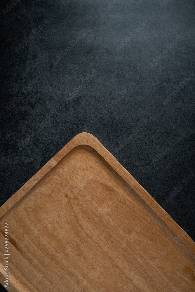 An empty wooden tray on a black background