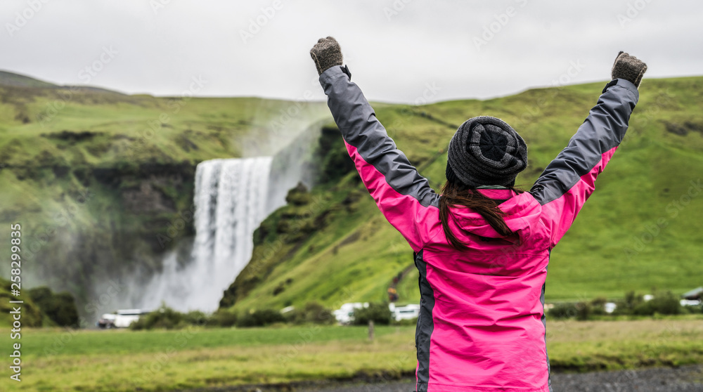 Woman traveler at beautiful scenery of the majestic Skogafoss Waterfall in countryside of Iceland in