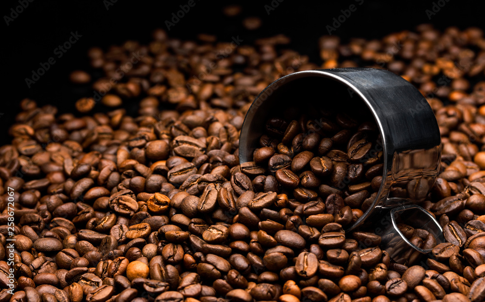 Pile of coffee beans with metal cup, close up, dark background with copy space, shallow depth of fie