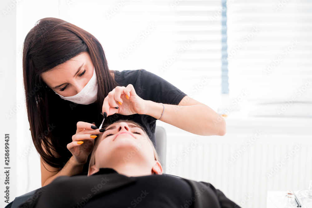 Pretty girl getting brow depilation at beauty salon