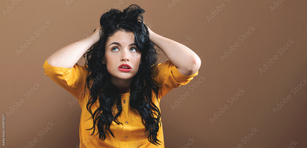 Young woman feeling stressed on a solid background