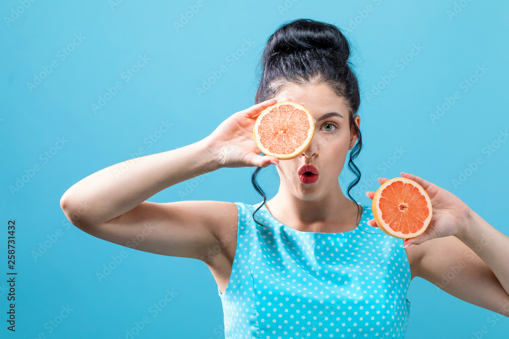 Young woman holding oranges on a blue background