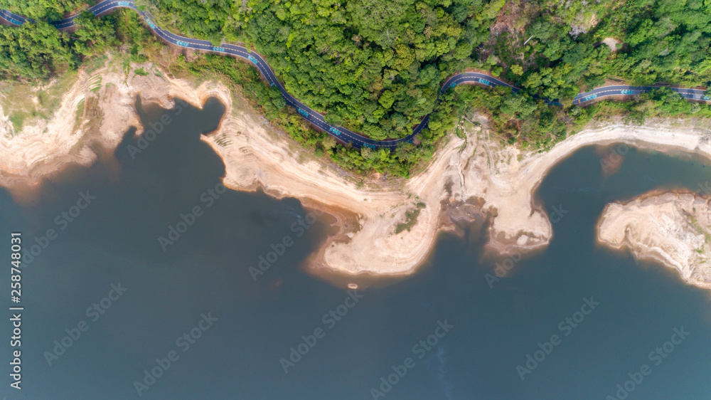 Top down from Drone aerial view of rainforest with asphalt road around the dam