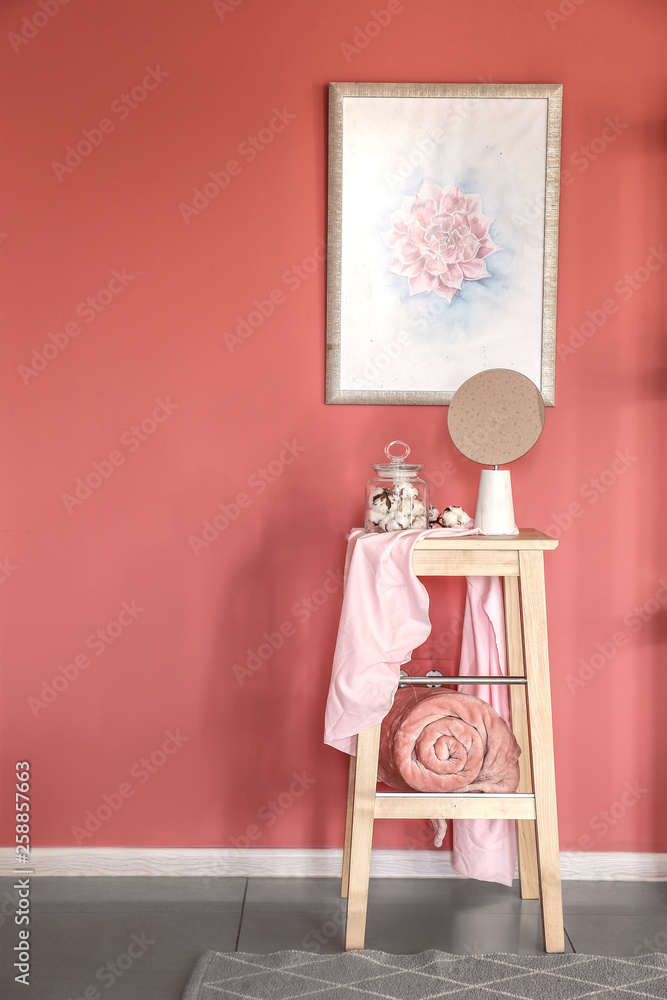 Wooden stool with decor near color wall in room