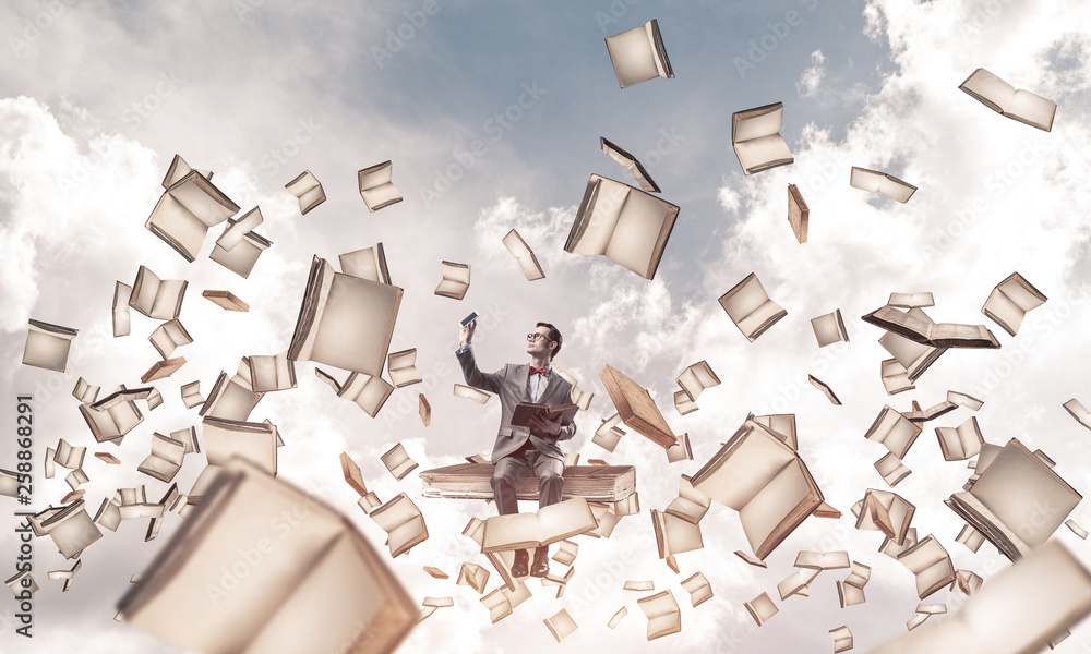 Young businessman or student studying the science and books fly around