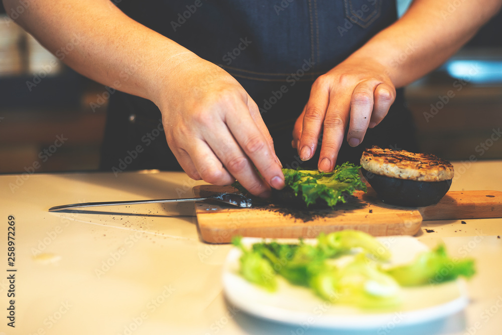 close up on hands man chef preparing delicious burger at kitchen