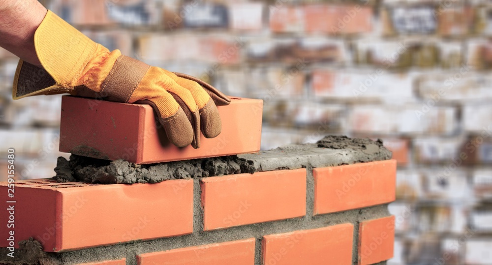 Worker builds a brick wall in the