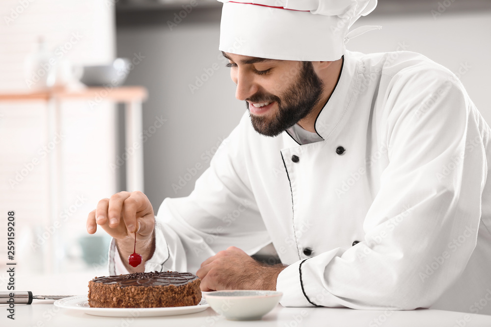 男糖果师在厨房装饰美味的巧克力蛋糕