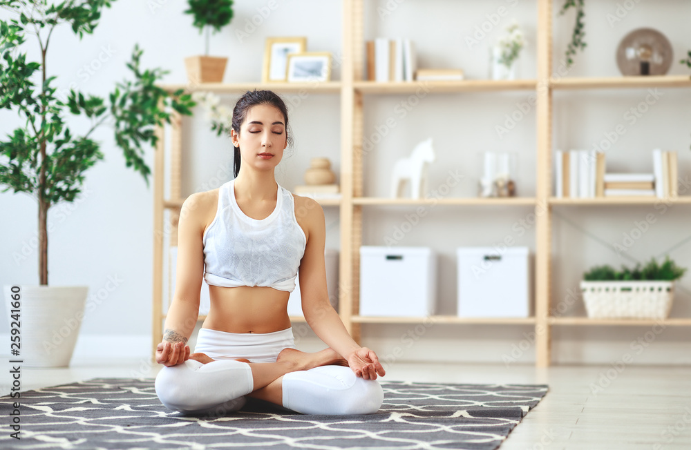 woman doing yoga, meditating in Lotus position at home