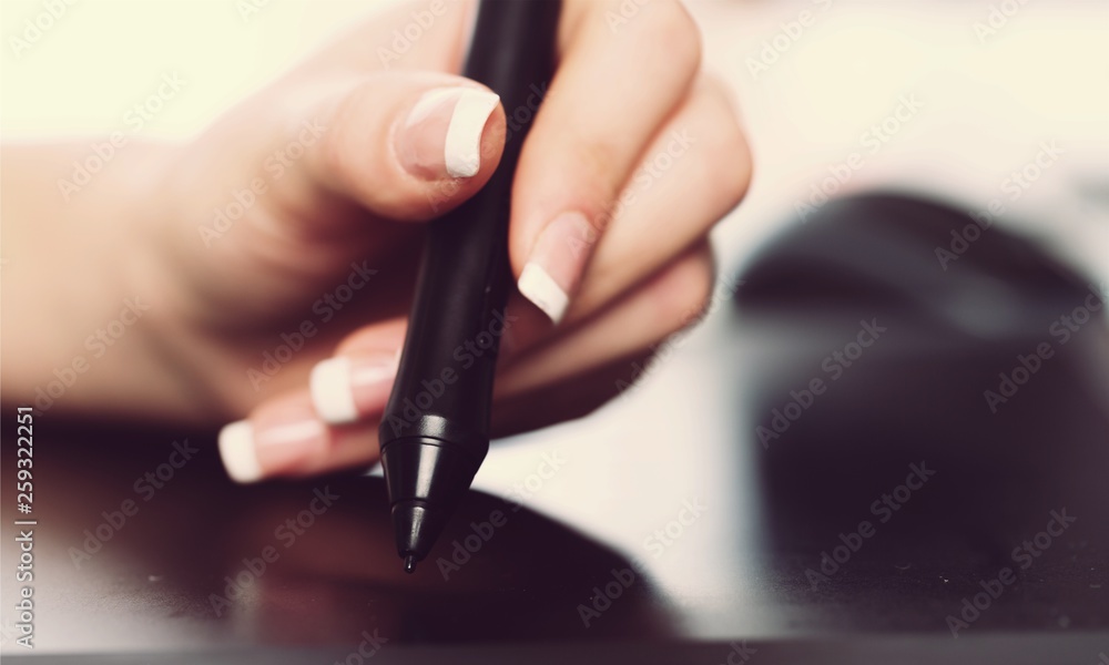 Hand of the designer with a pen on a tablet