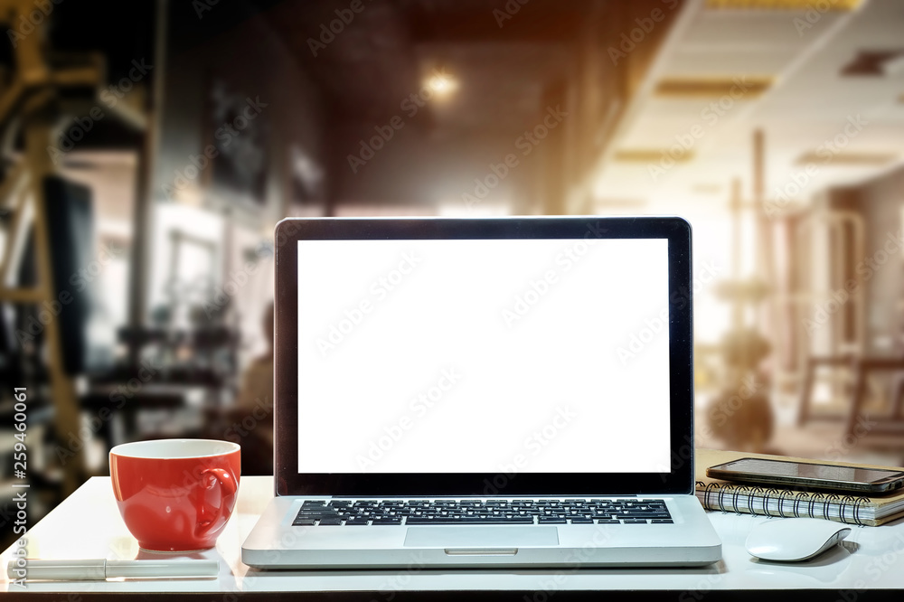 Front view of cup and laptop, smartphone, and tablet on table in Office in fitness gym in morning li