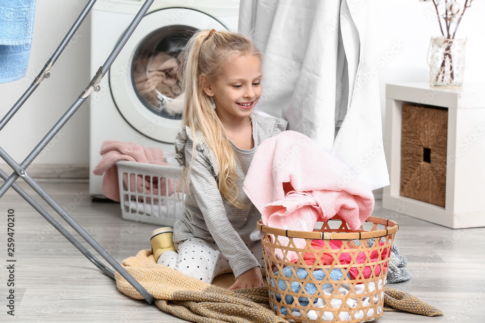 Little girl with clean laundry after washing at home