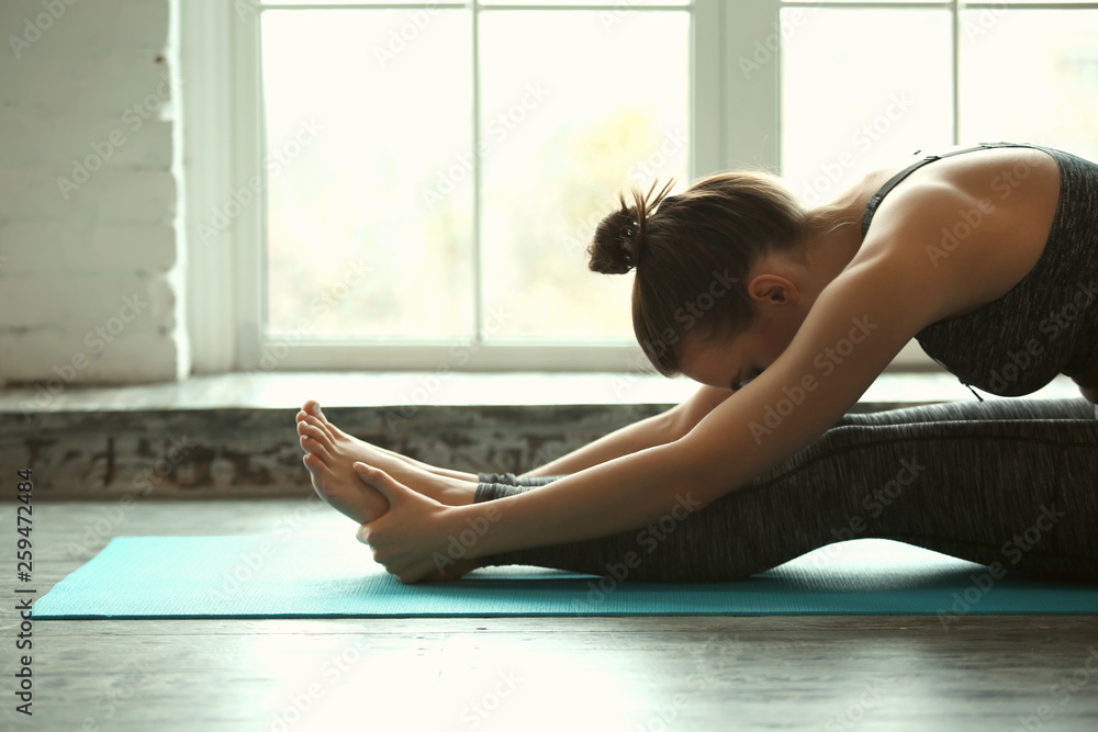 Beautiful young woman doing yoga at home