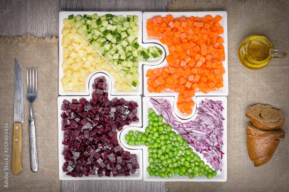 .Raw vegetables carrots, peas, onions, cucumber, potatoes, beets cut into cubes lie on puzzles in th