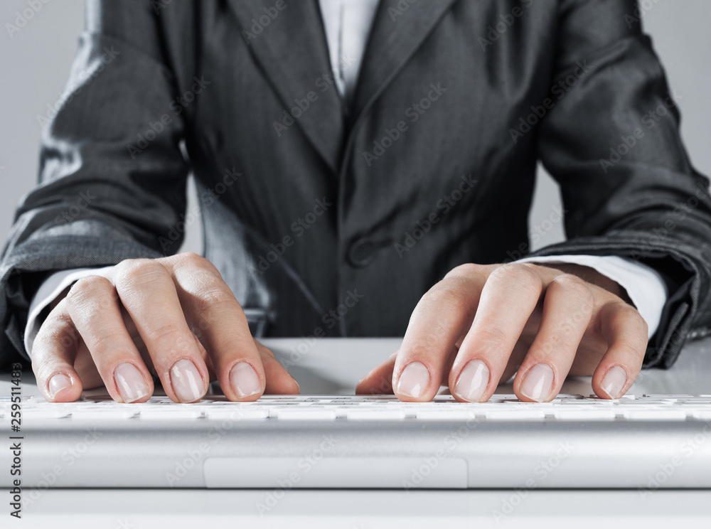 Closeup of businesswoman hand typing on keyboard with mouse on wood table