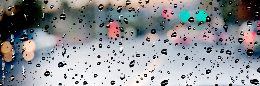 Rain drops on car window with blurred street traffic