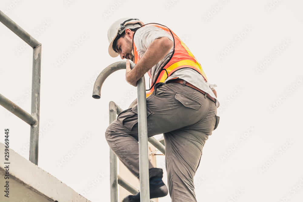 年轻的建筑工人或工程师在建筑物顶部爬梯子。工程项目混凝土