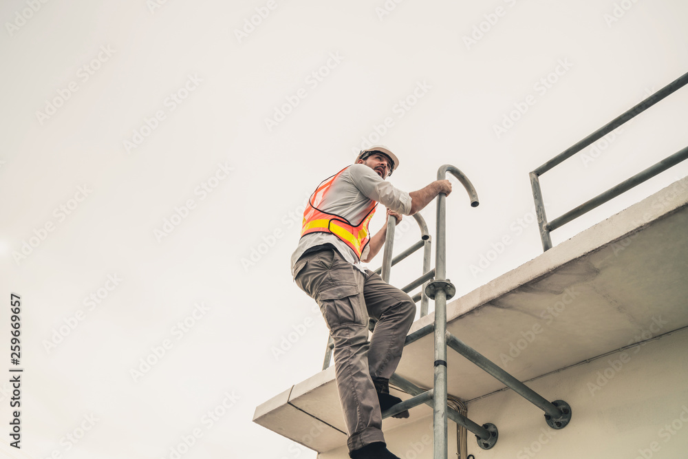 年轻的建筑工人或工程师在建筑物顶部爬梯子。工程项目混凝土