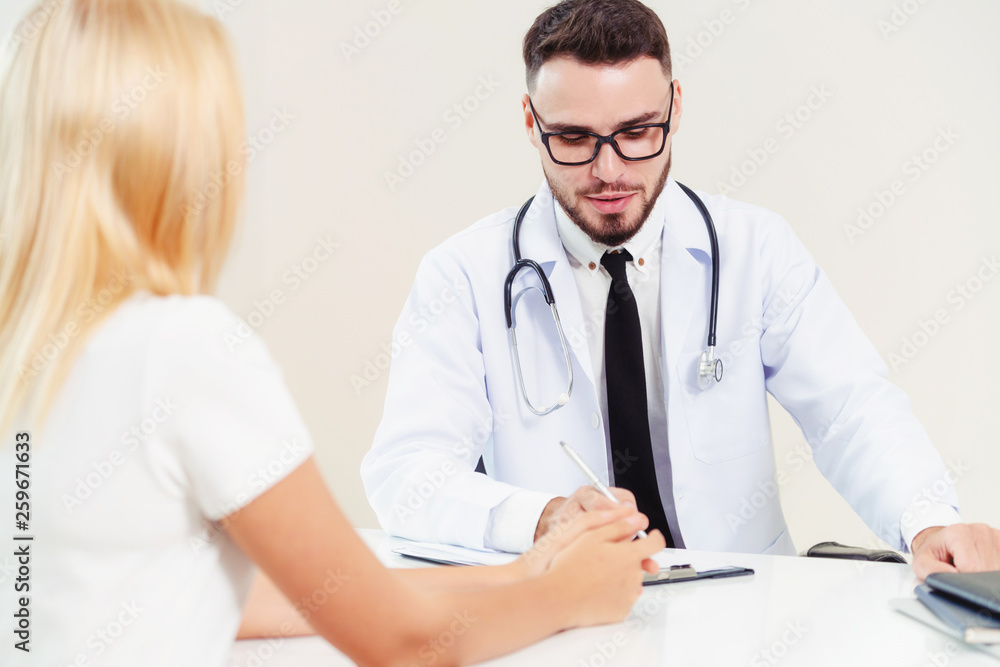 Male doctor is talking to female patient in hospital office. Healthcare and medical service.