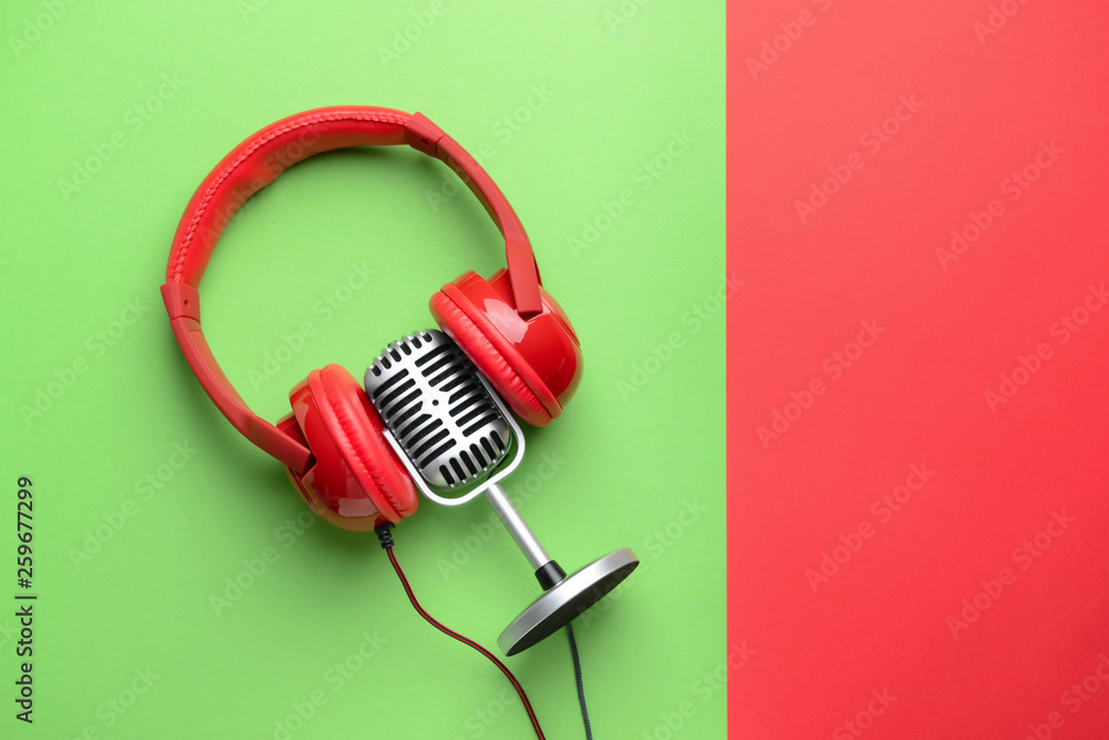 Retro microphone and headphones on color background