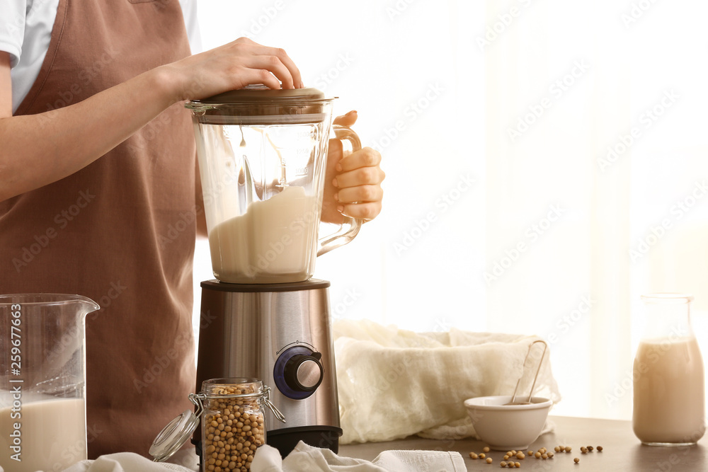 Woman making soy milk in kitchen