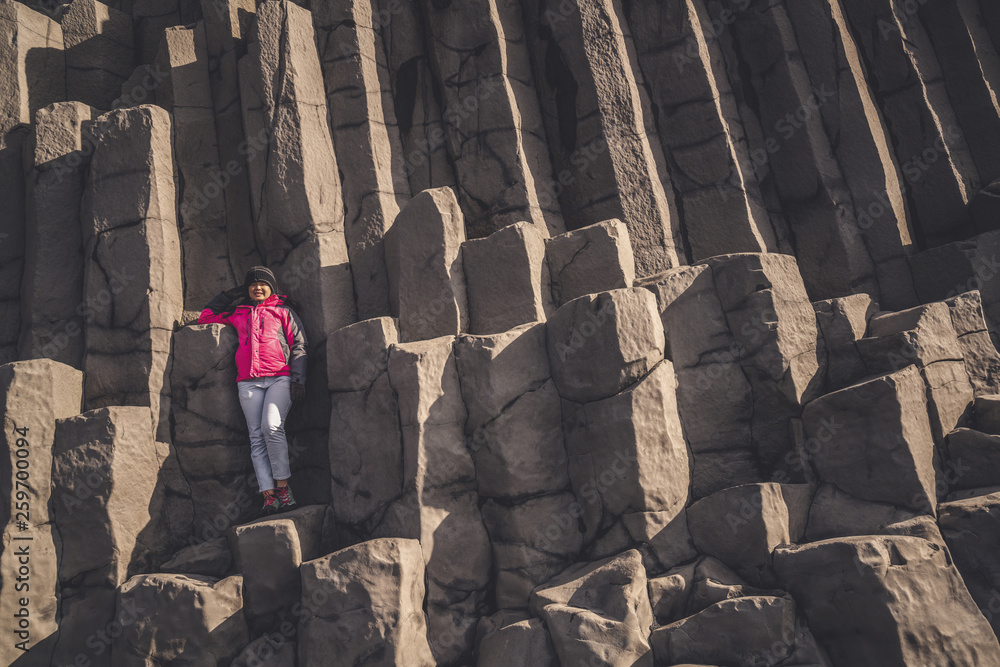 Traveler travel to unique volcanic rock formation on Iceland black sand beach located near the villa