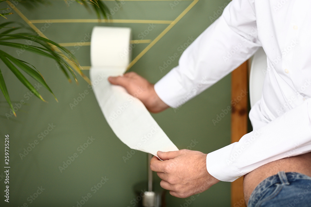 Man tearing off toilet paper in WC