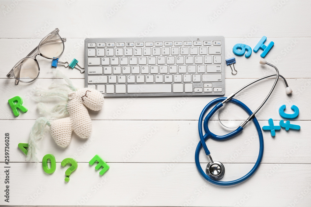 Composition with PC keyboard, stethoscope and toy on white wooden background