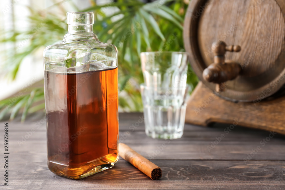 Bottle of cold whiskey with cigar on wooden table