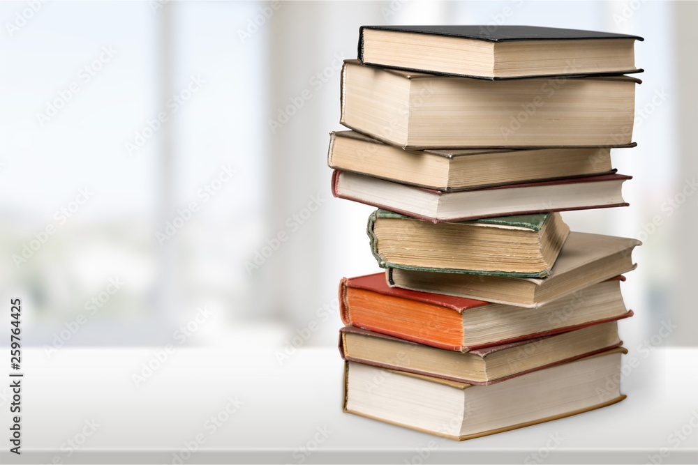 Stack of books with laptop on table