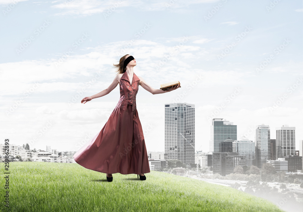 Girl against cloudy sky with opened book in palm as idea for knowledge