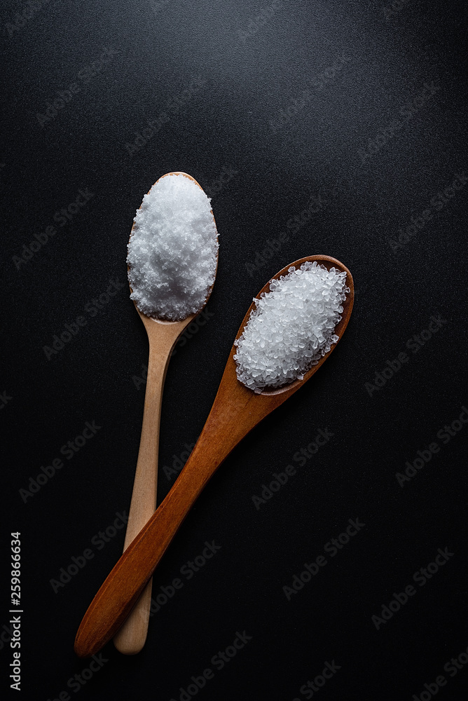 Coarse sea salt and fine salt on black background