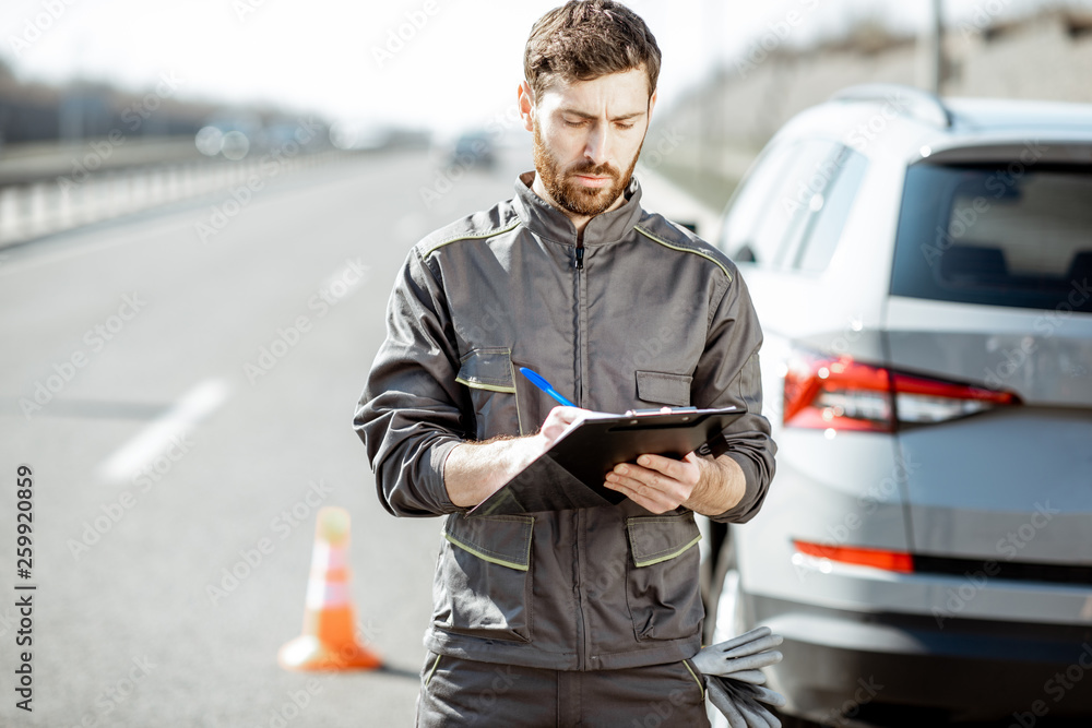 身穿制服的道路救援人员站在高速公路上破碎的汽车附近签署一些文件