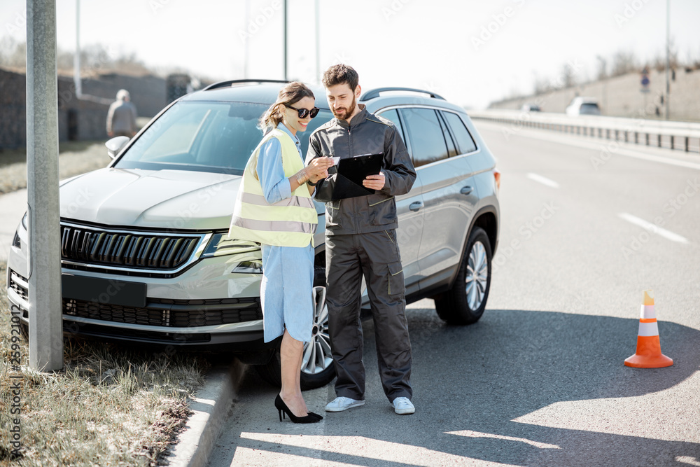 在t上发生的道路事故中，一名妇女与道路救援人员站在汽车附近签署了一些文件