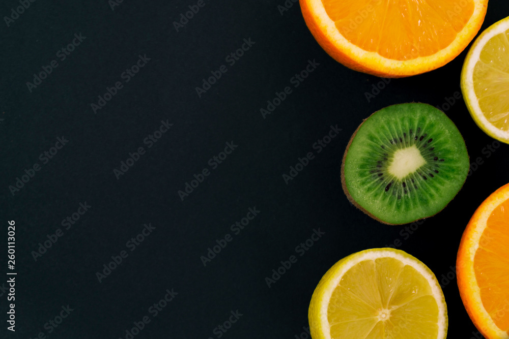 Colorful fresh fruits on a dark background. Orange, mandarin, kiwi, lemon. Fruit background. Summer 