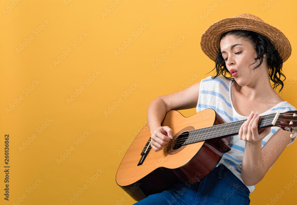 Young woman with a guitar on a yellow background