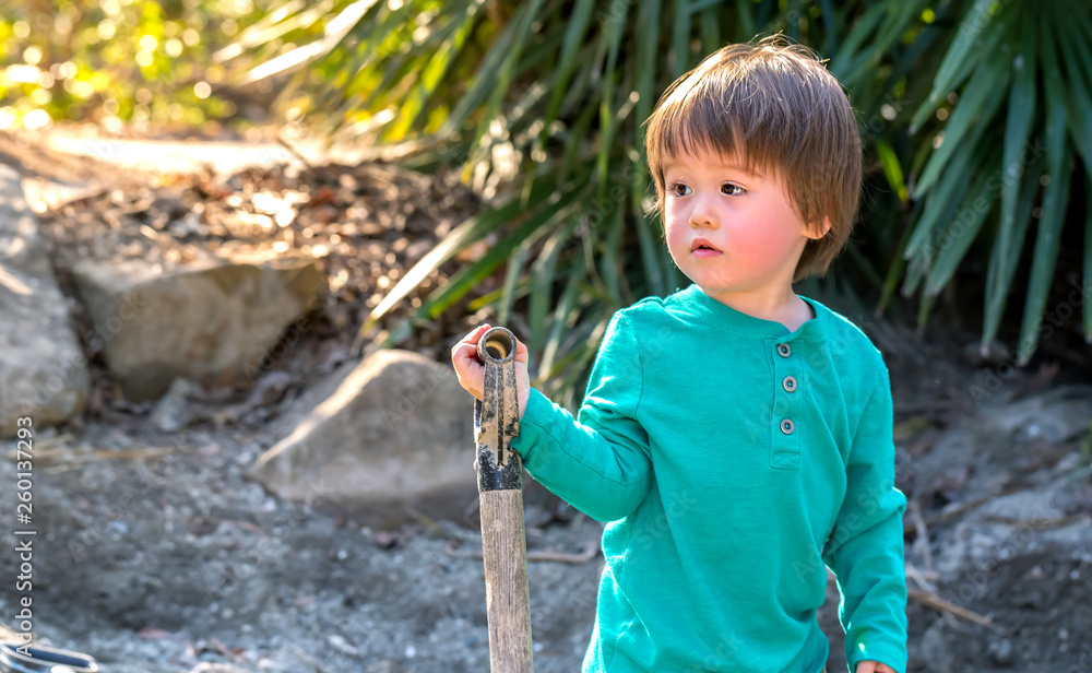 Toddler boy digging with a shovel outside