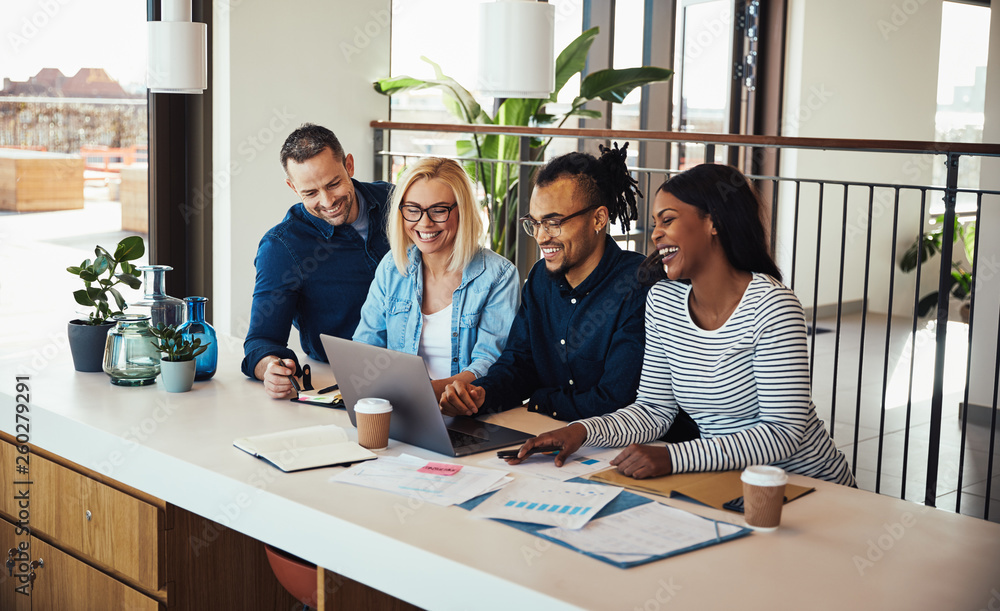 Smiling businesspeople working on a laptop at an office table