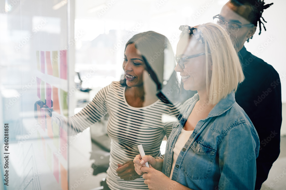 Smiling coworkers using sticky notes to brainstorm during a meet