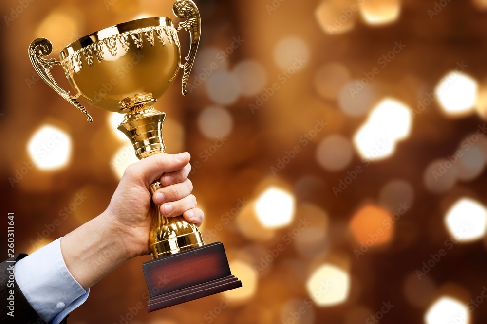 Hand holding golden trophy on blurred background