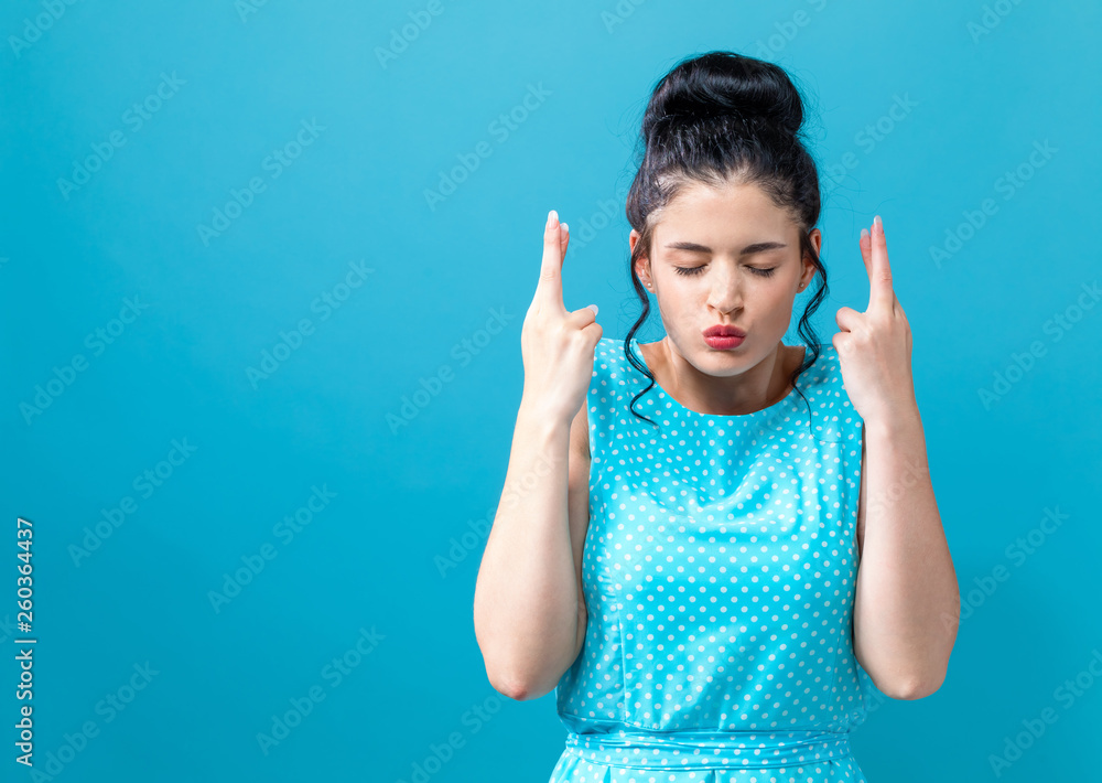 Young woman crossing her fingers and wishing for good luck