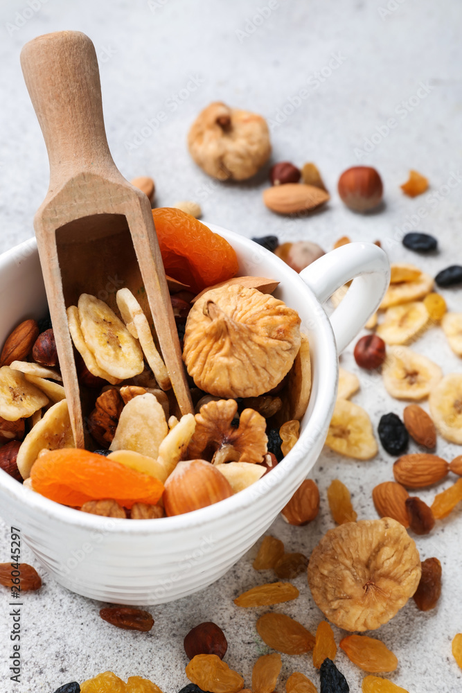 Cup and scoop with assortment of tasty dried fruits and nuts on table