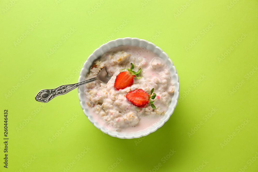 Bowl with tasty sweet oatmeal on color background