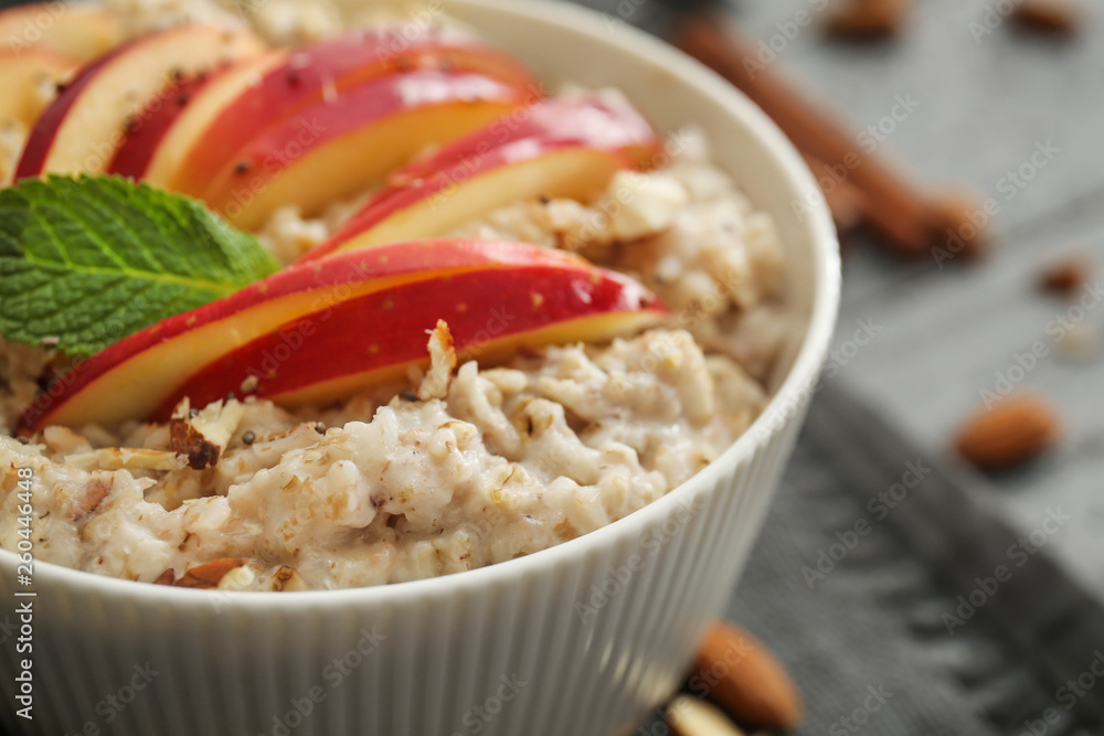 Bowl with tasty sweet oatmeal on table, closeup