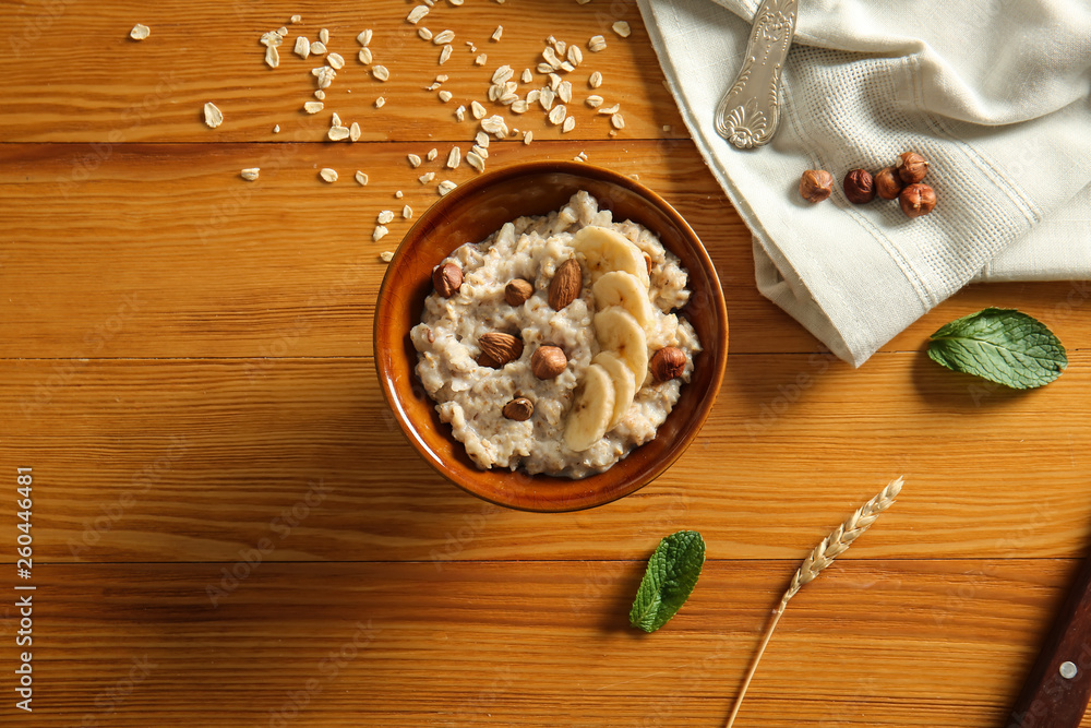 Bowl with tasty sweet oatmeal on wooden table